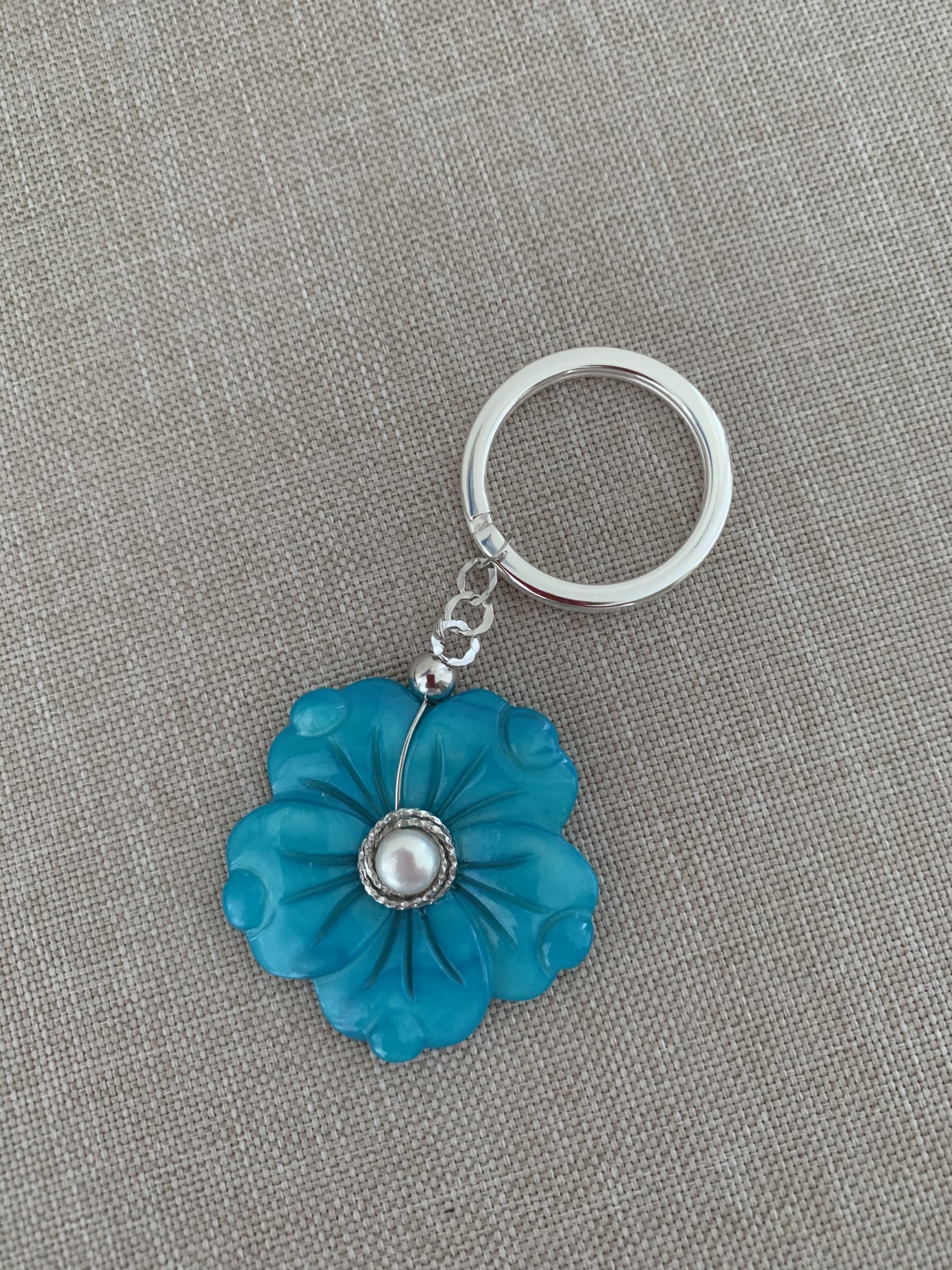 Portachiavi con fiore di madreperla azzurra, argento rodiato, perla coltivata e anello in acciaio