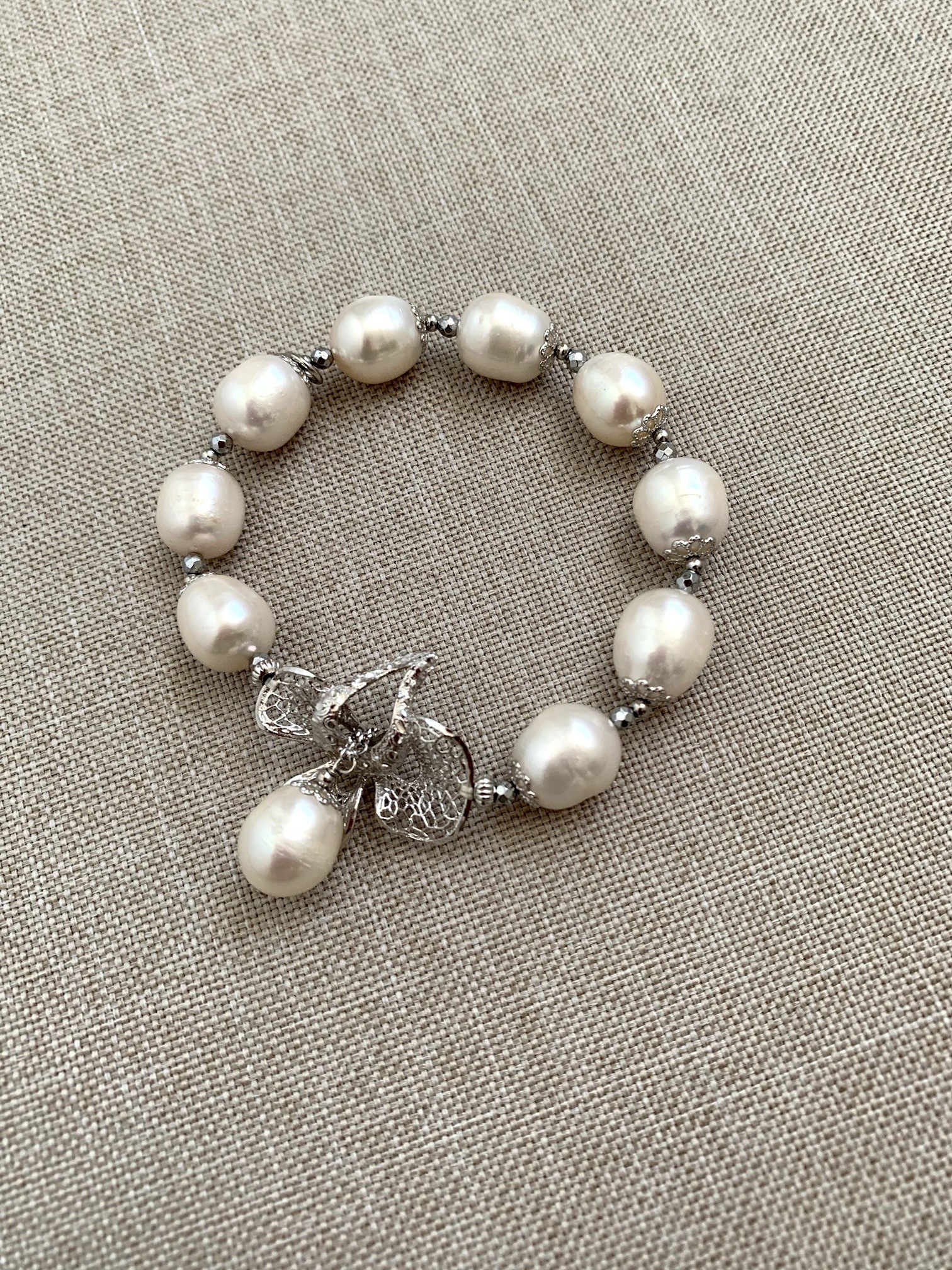 Bracciale elastico di perle bianche ed elemento a fiore in argento rodiato